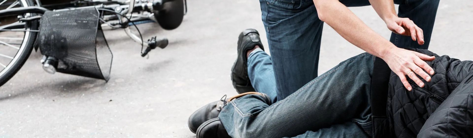 Man checking on a bicyclist after hitting them with a vehicle.