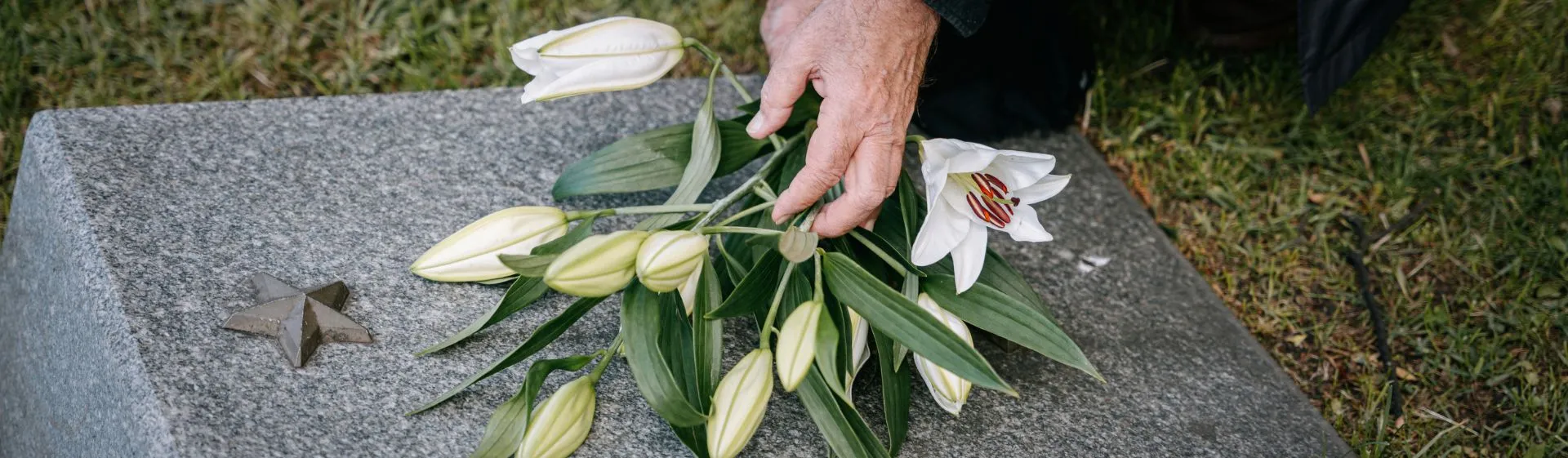 Person putting flowers onto a tombstone.