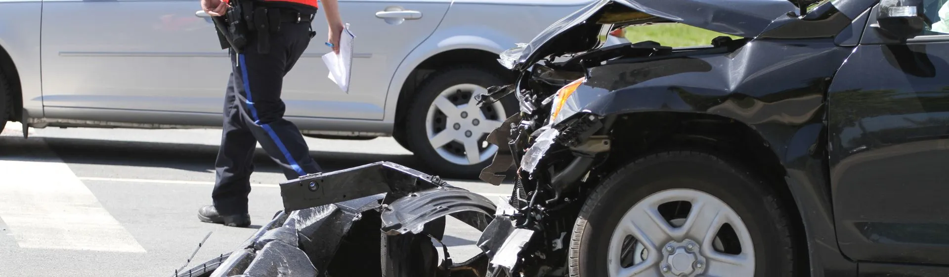 Two cars damaged after an accident. A police presence is on sight making a report.